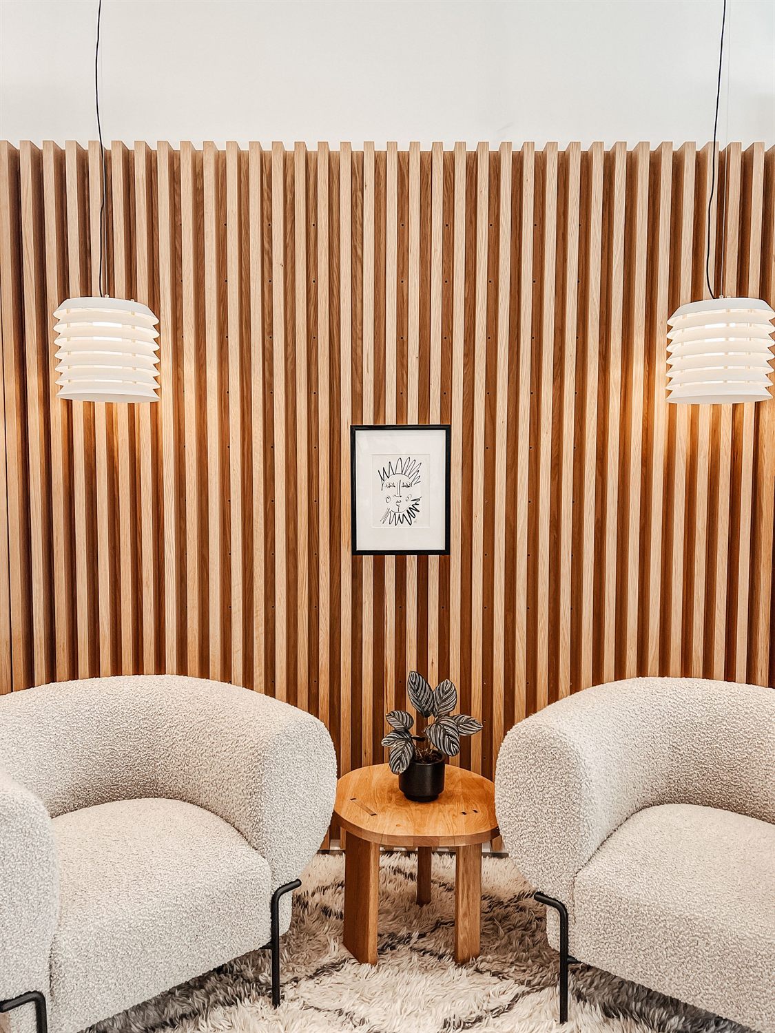 Two comfortable armchairs beside a small table and a potted plant in soft natural light