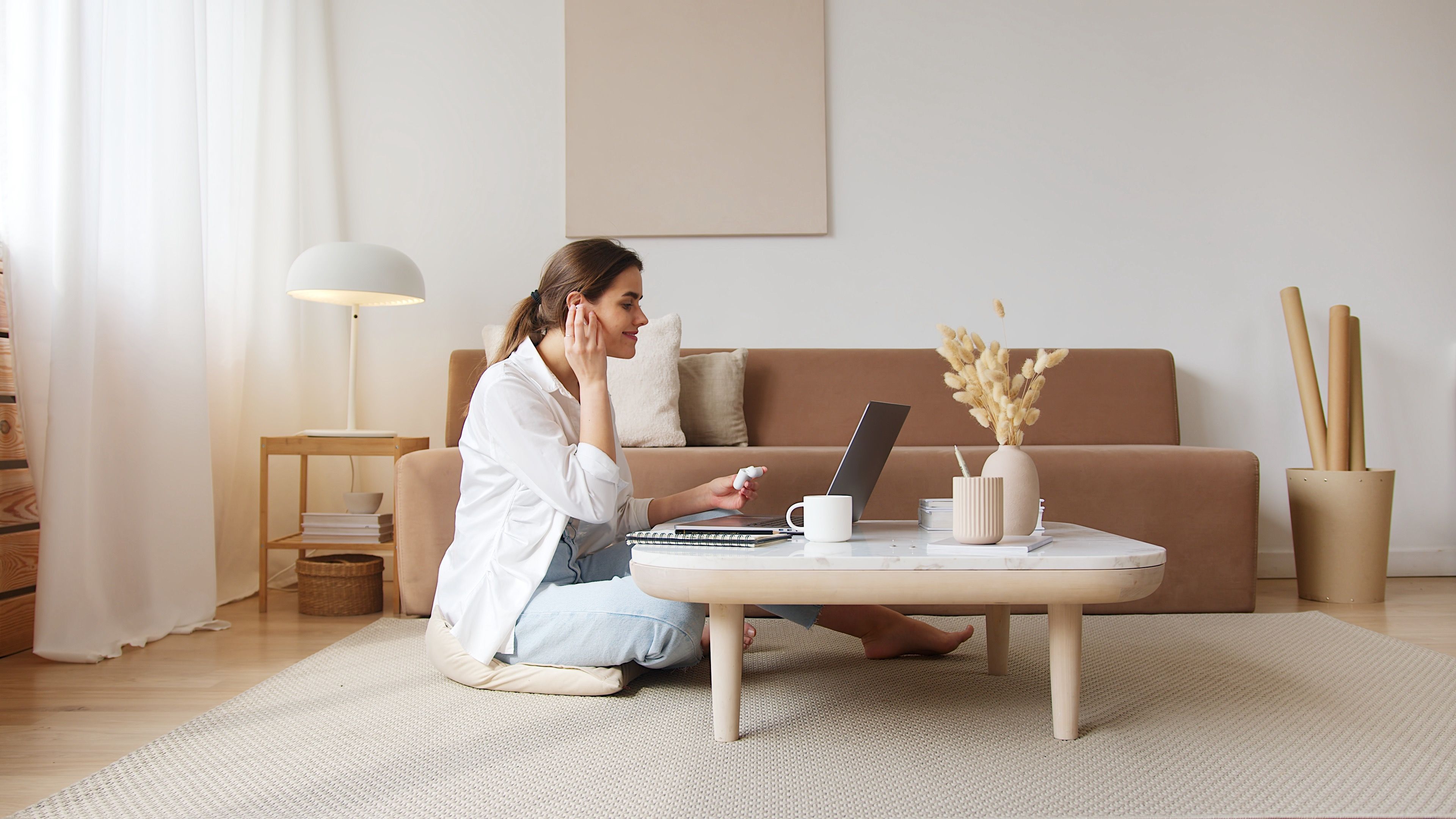 A woman on a video call at a low table in a calm, warm living room